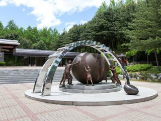 南北韩人民从两侧推着半球的铜像，象征着合二为一